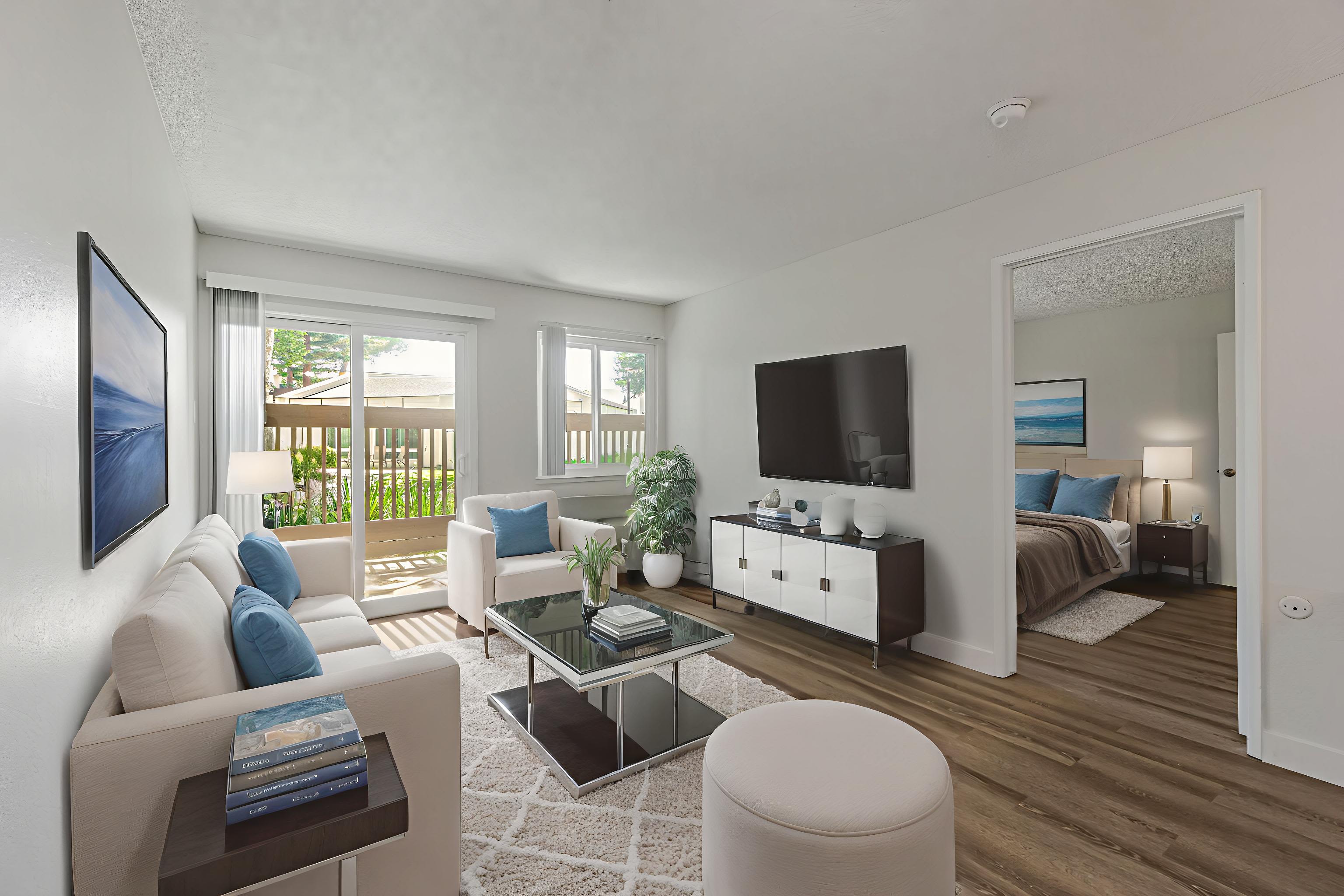 Modern living room with sofa, TV, and patio door overlooking greenery at Clayton Gardens in Concord, California