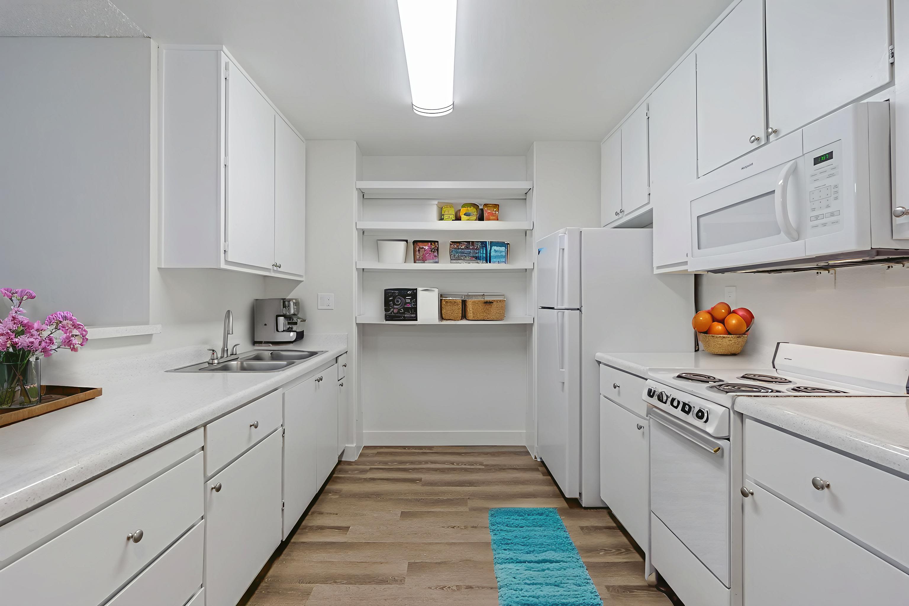 Bright kitchen with white cabinets, modern appliances, and open shelving at Clayton Gardens in Concord, California