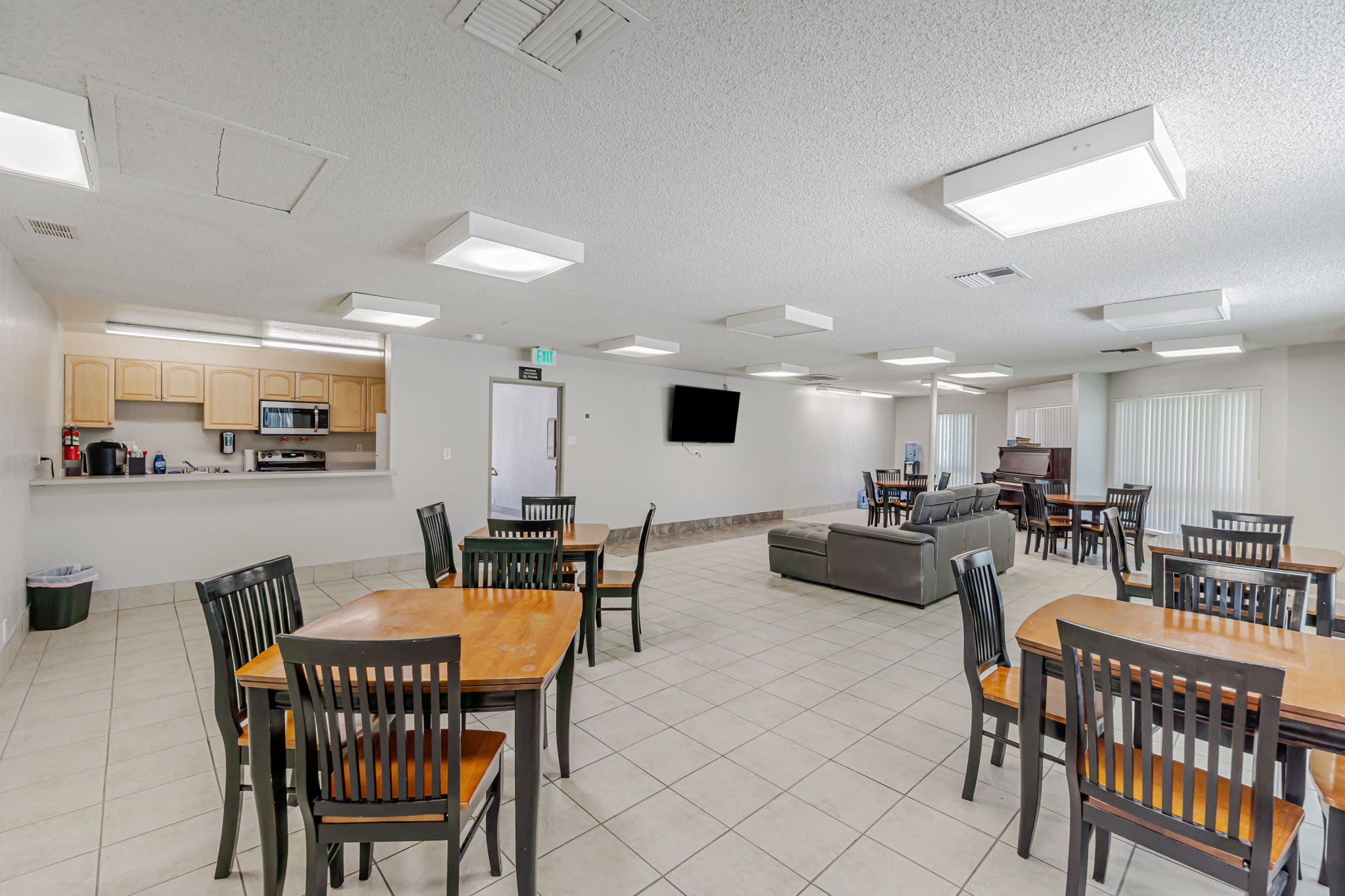 Community room with tables, chairs, sofa seating, and an open kitchen area at Clayton Gardens in Concord, California