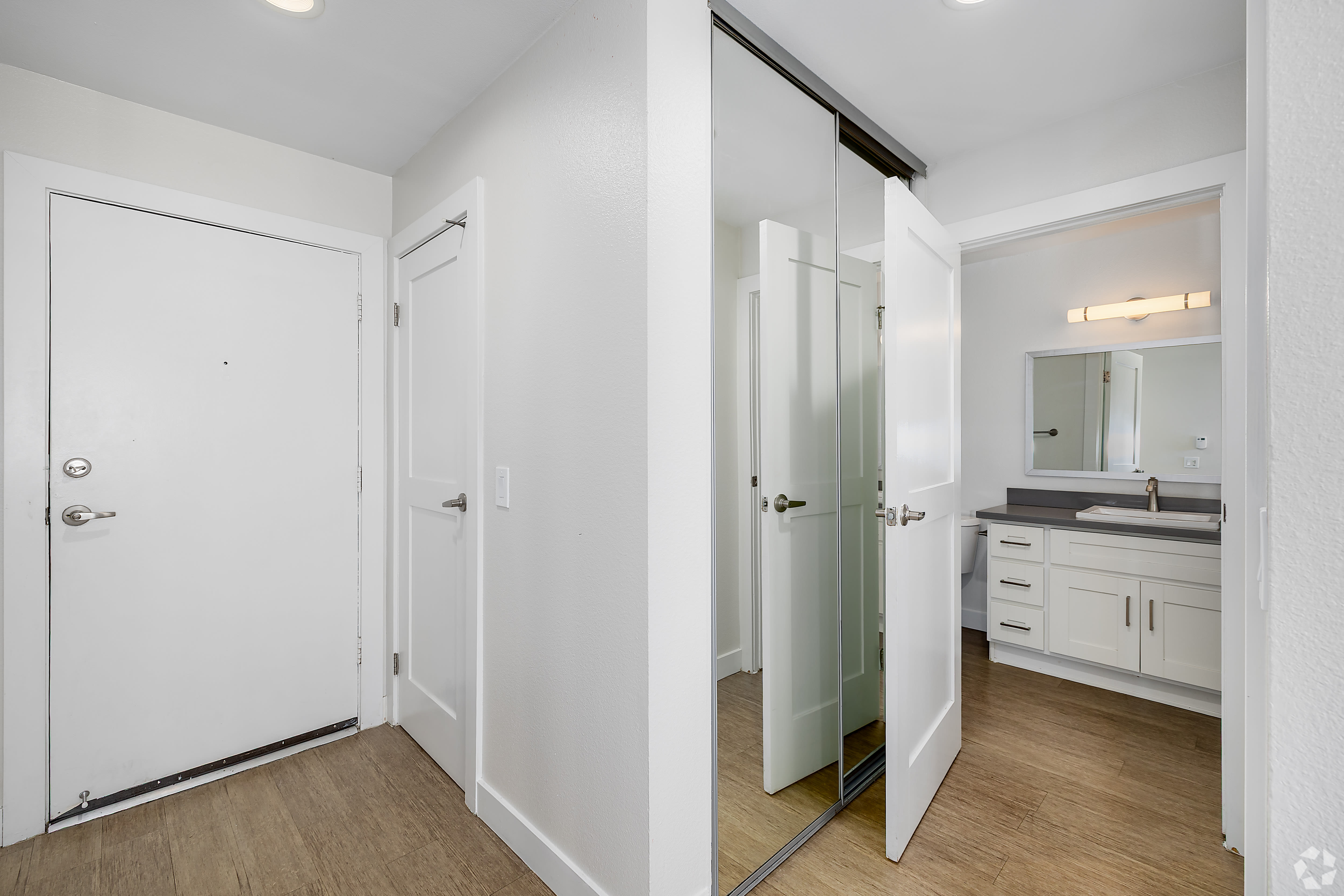 Entry hallway with mirrored closet and view into modern bathroom at Beck Park in North Hollywood, California