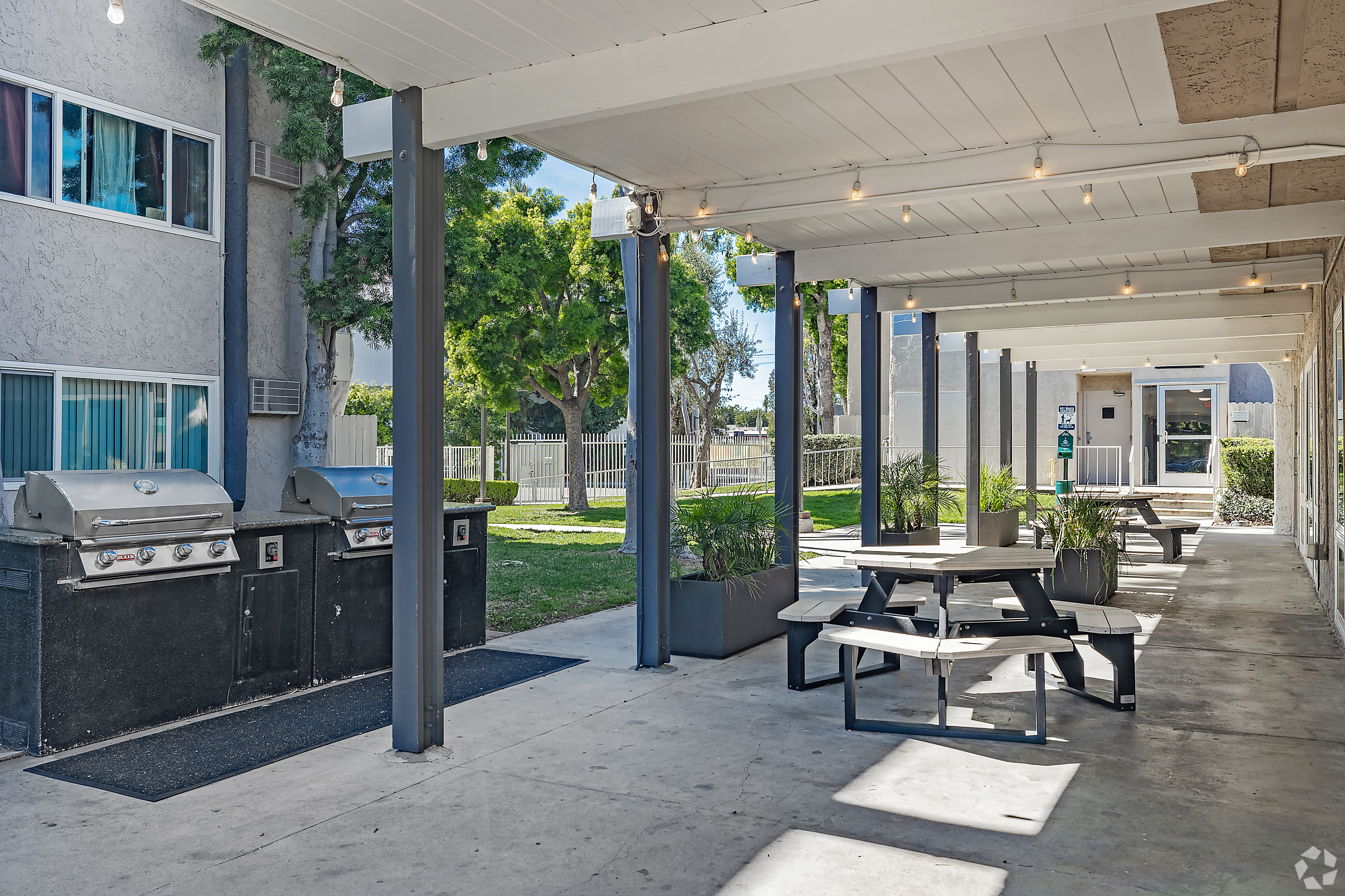 Covered outdoor BBQ area with grills, picnic tables, and greenery at Beck Park in North Hollywood, California