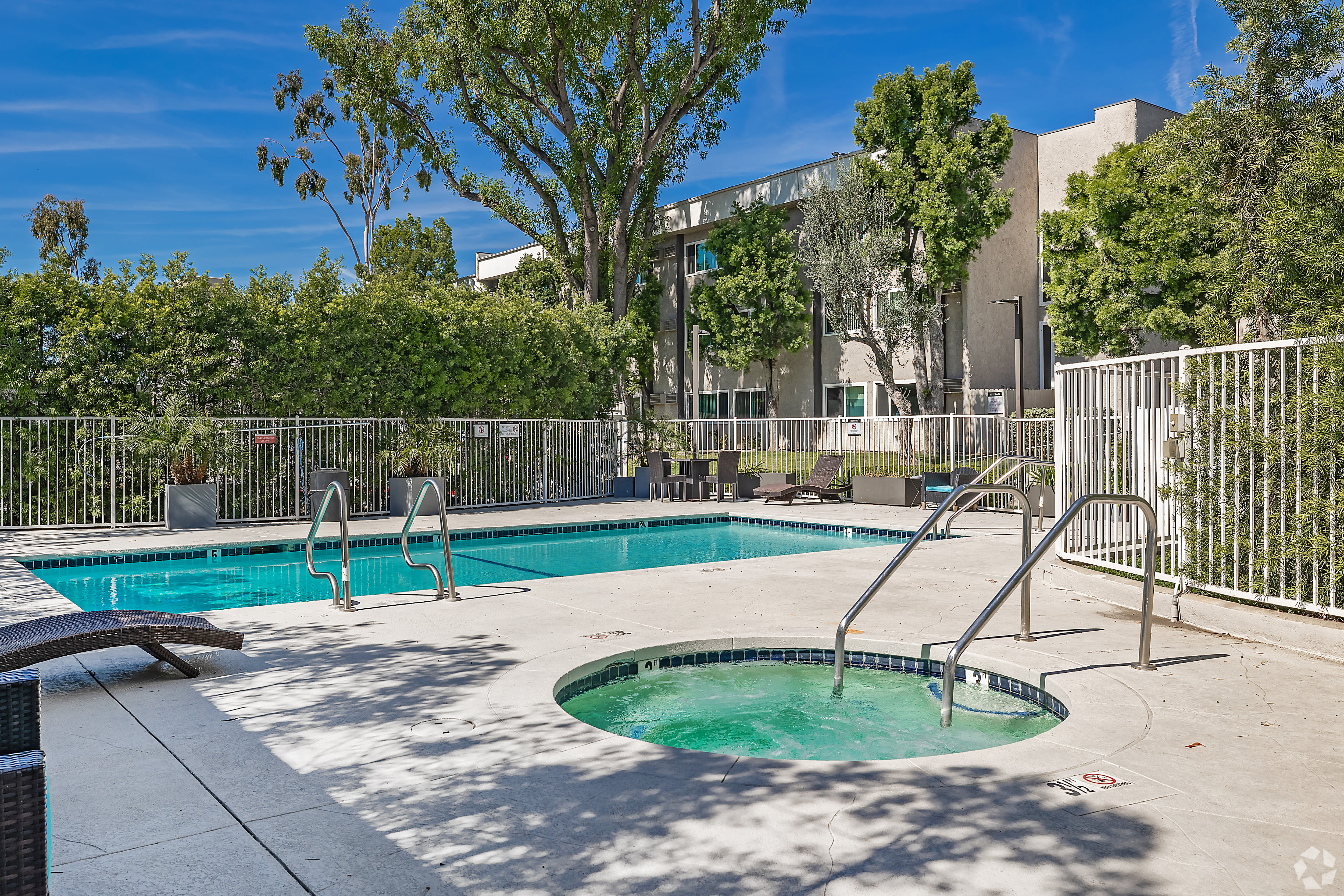 Outdoor pool and spa area with fenced surroundings and greenery at Beck Park in North Hollywood, California