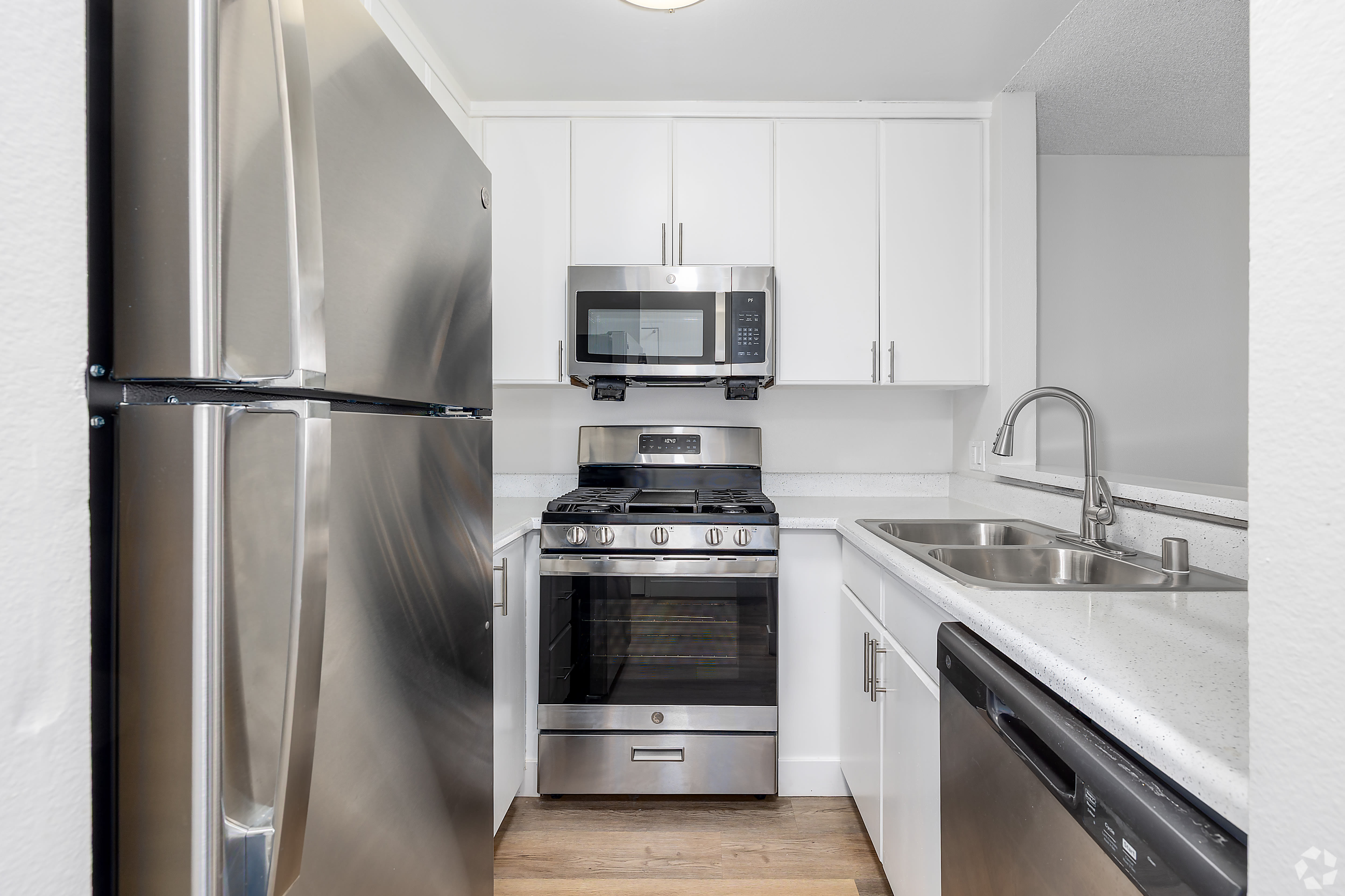 Small kitchen with stainless fridge, gas stove, microwave, and white cabinets at Beck Park in North Hollywood, California