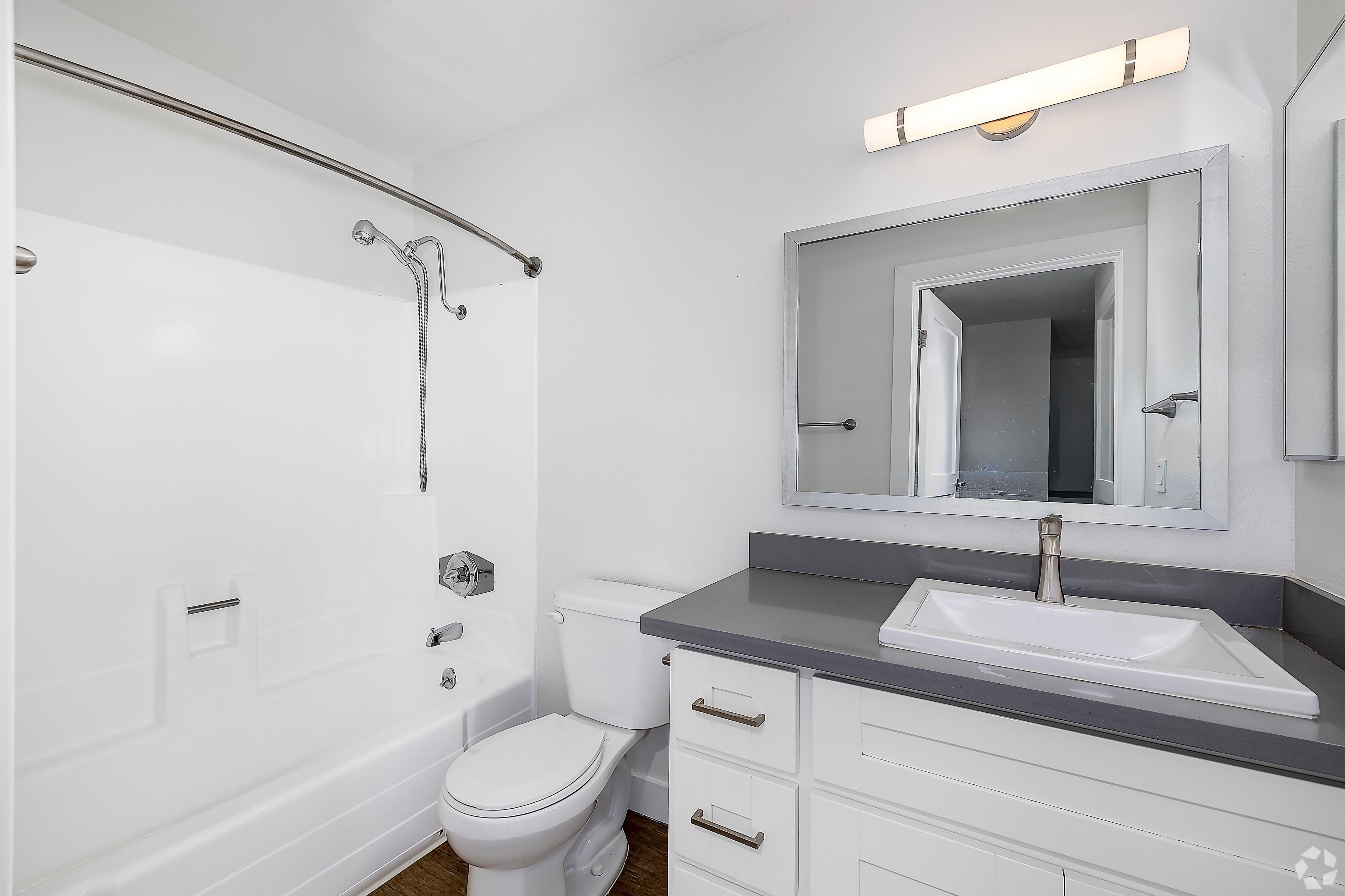 Updated bathroom with gray countertop, large mirror, and shower-tub at Beck Park in North Hollywood, California