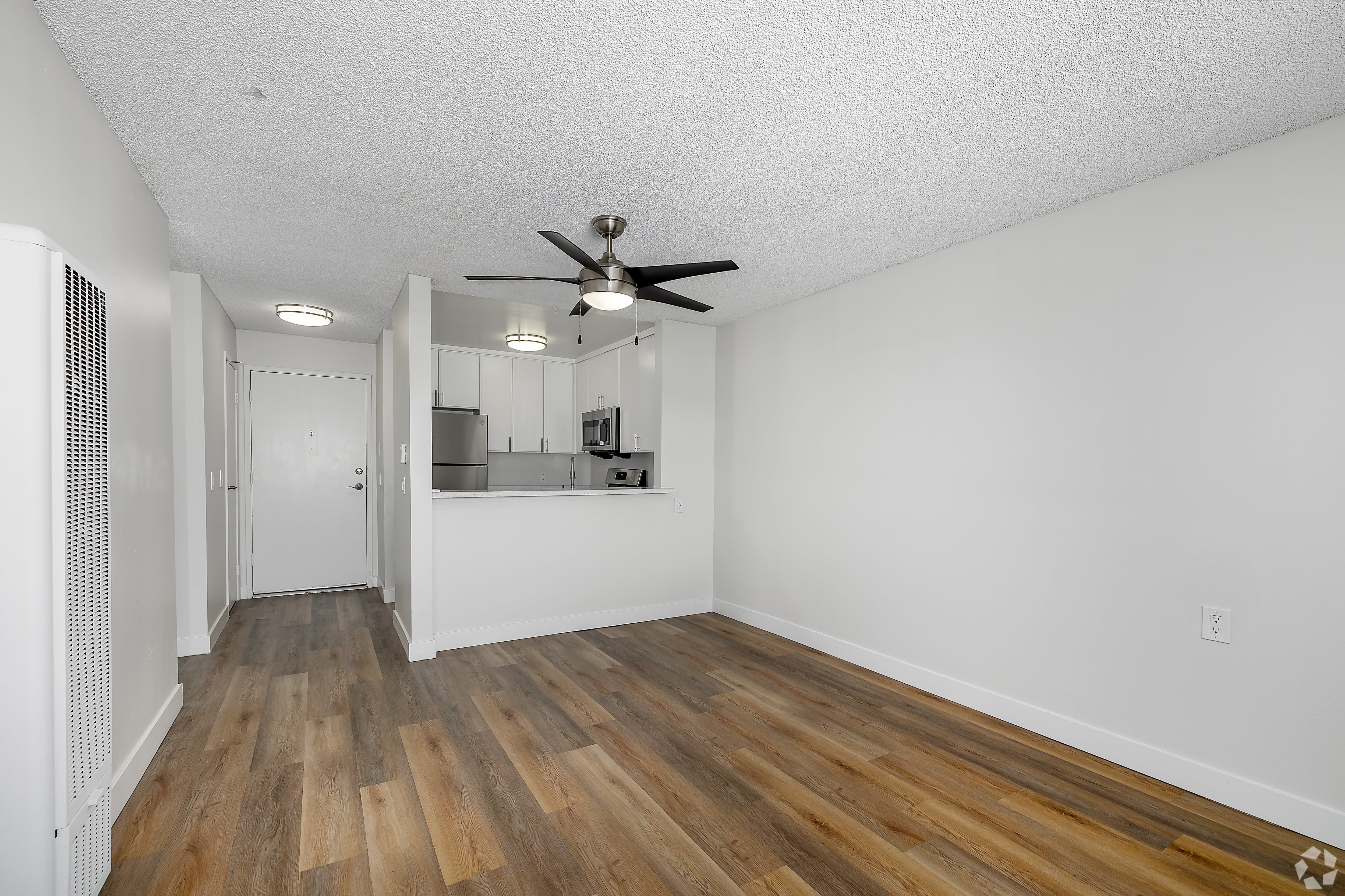 Open living area with wood flooring, ceiling fan, and kitchen view at Beck Park in North Hollywood, California