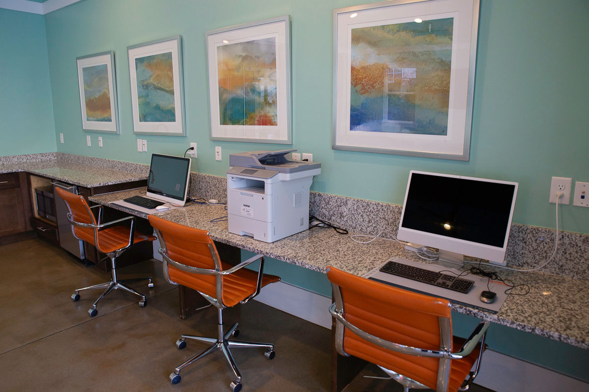 Desk along teal wall with artwork and three workstations