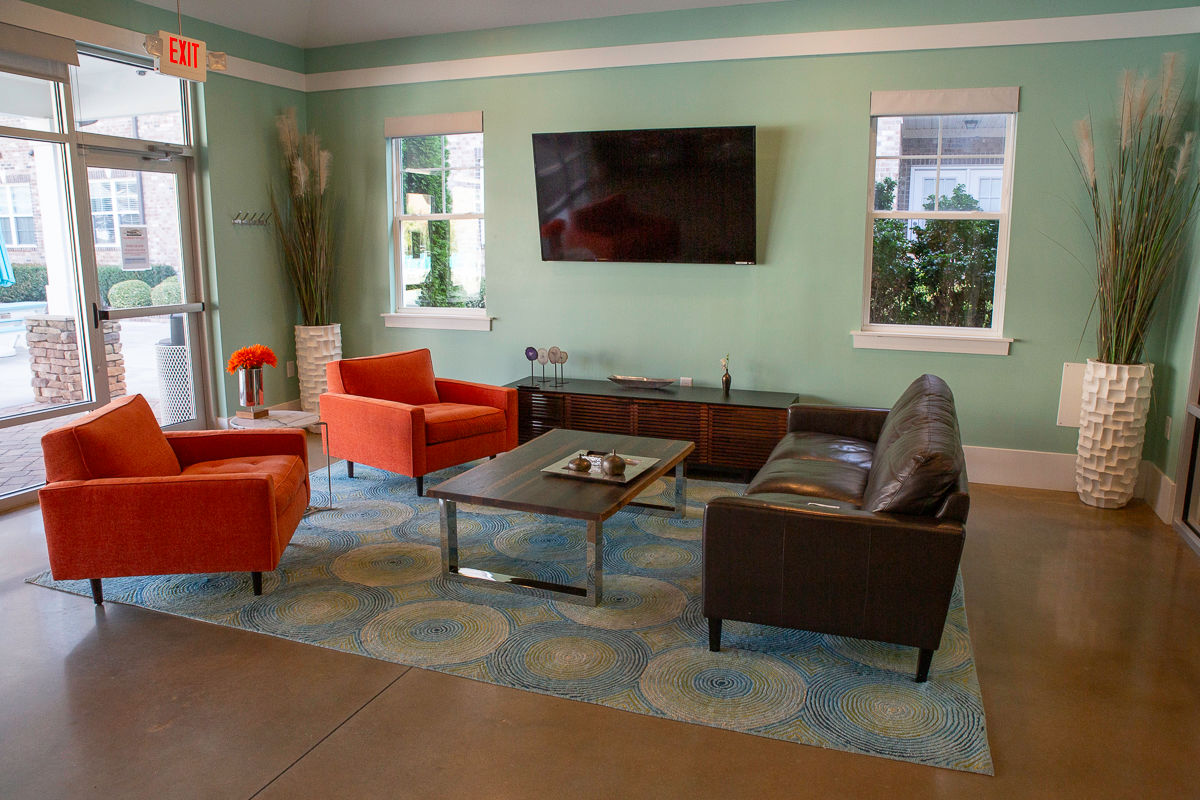 Room with green walls and chairs around a coffee table with TV mounted to wall