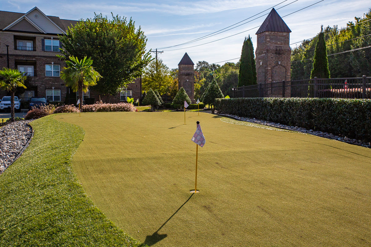 Putting green with flag in hole and buildings in background