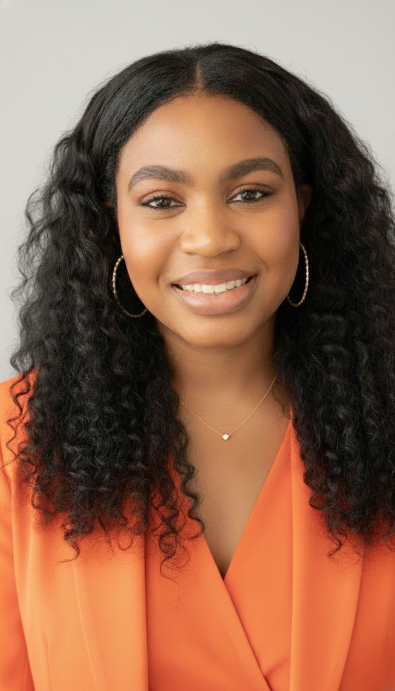 Team member headshot in orange blouse, studio portrait at ATX Fenton in Austin, Texas