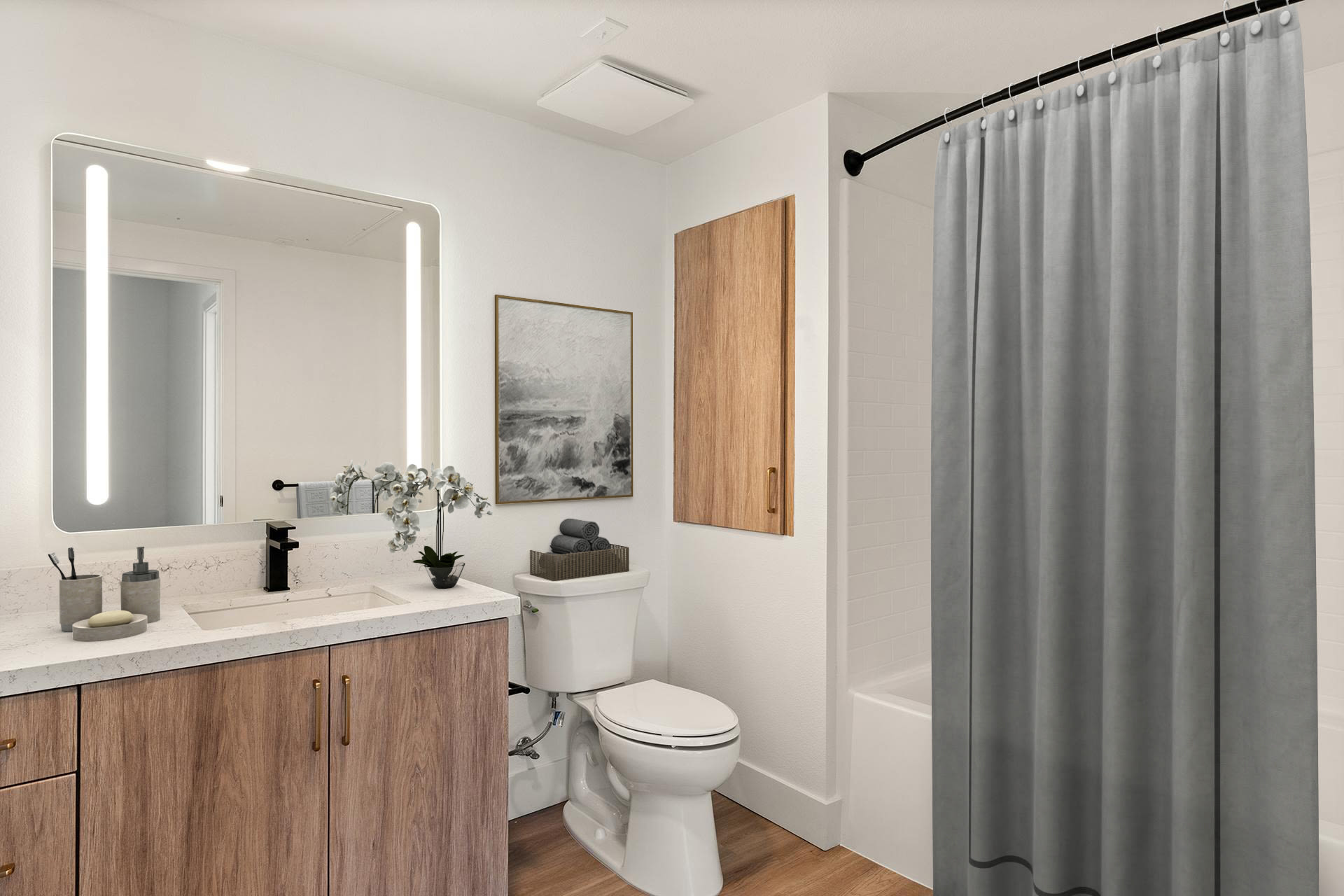 Modern bathroom with vanity, illuminated mirror, toilet, and tub shower at Colony Parc in Ventura, California