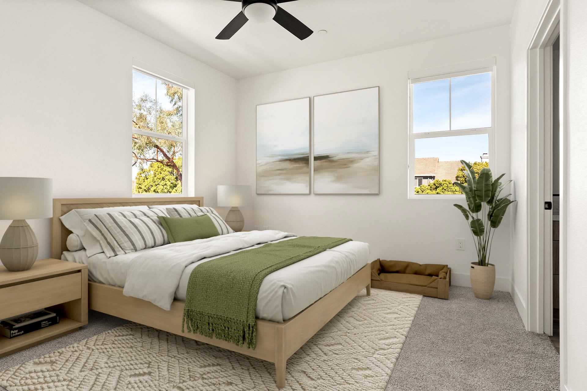 Cozy bedroom with wood bed frame, ceiling fan, and large windows at Colony Parc in Ventura, California