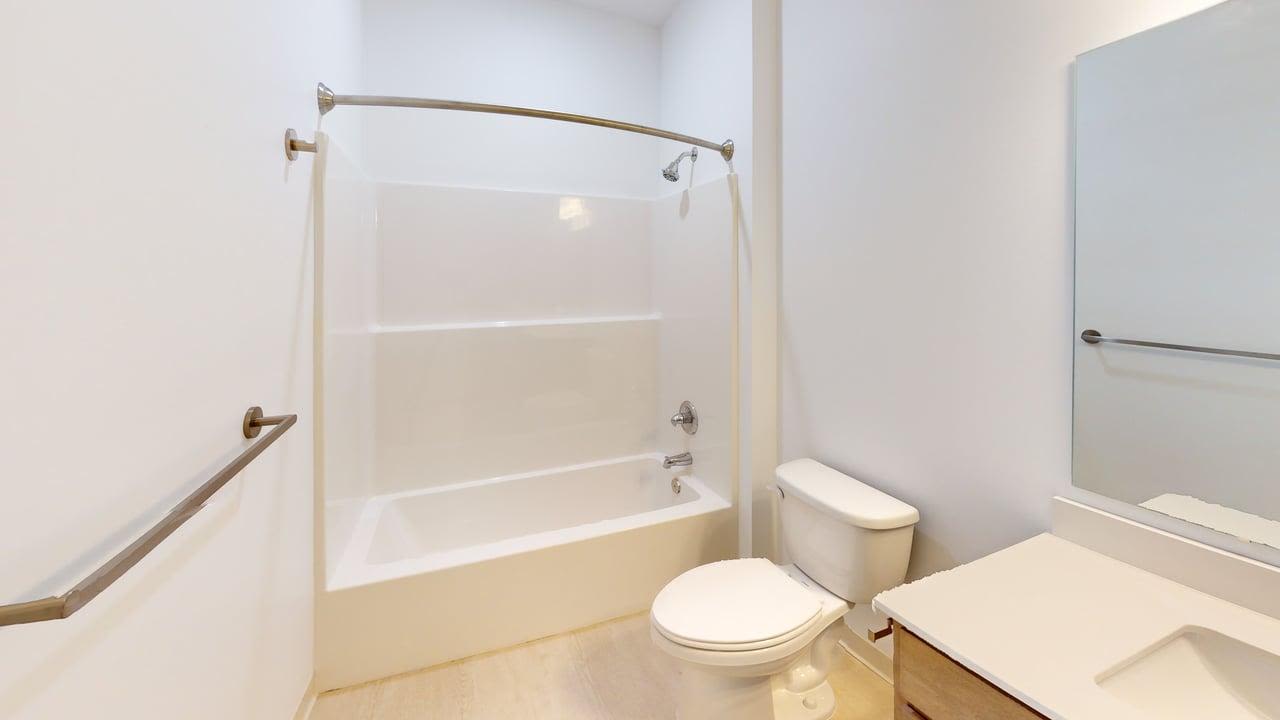 Modern bathroom with tub-shower combo, toilet, vanity, and bright white finishes at Terra Station in Hudsonville, Michigan