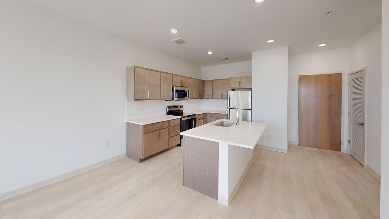Open kitchen with island, wood cabinets, stainless steel appliances, and recessed lighting at Terra Station in Hudsonville, Michigan