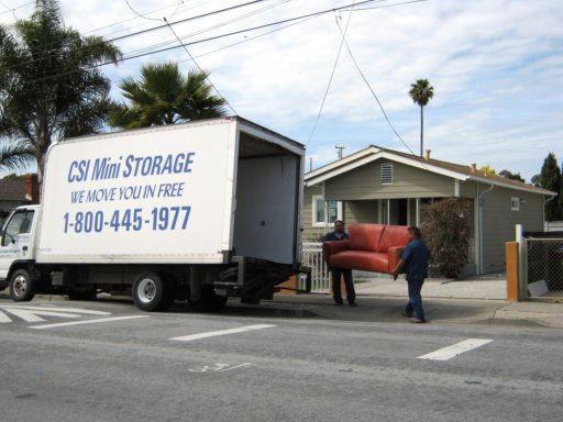 Two movers carrying a couch from a CSI Mini Storage moving truck for free scheduled move-in help in Richmond CA
