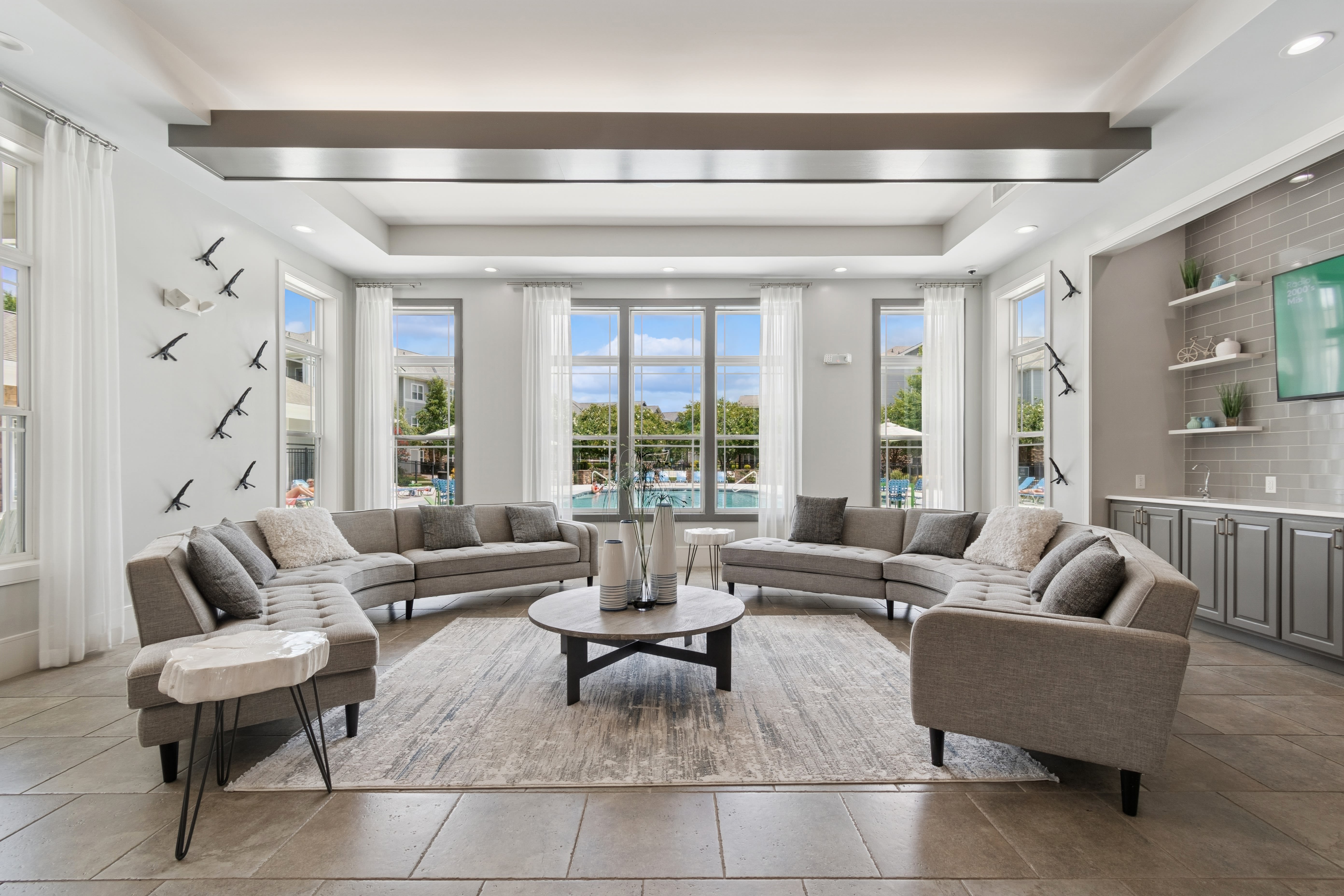 Modern apartment living room with open kitchen, light flooring, neutral walls, and large window for natural light at Photo Gallery | Evergreen at Five Points in Valdosta, Georgia