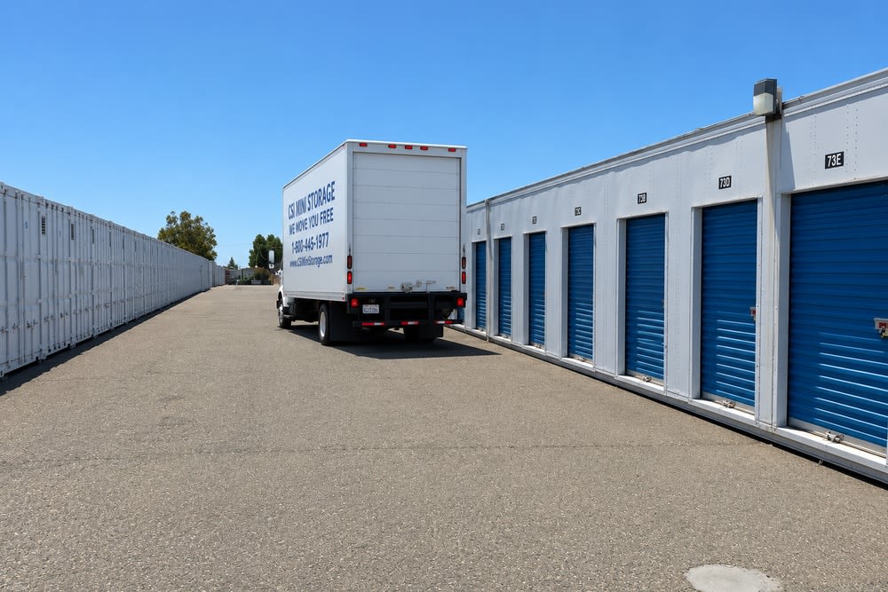 Wide drive aisle with rows of ground-floor drive-up storage units and a commercial box truck at CSI Mini Storage Alameda.