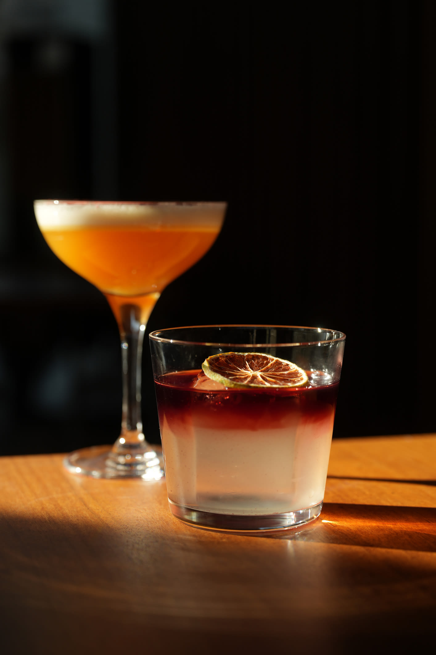Two cocktails on a table with light streaming through them at The Colton in Redwood City, California