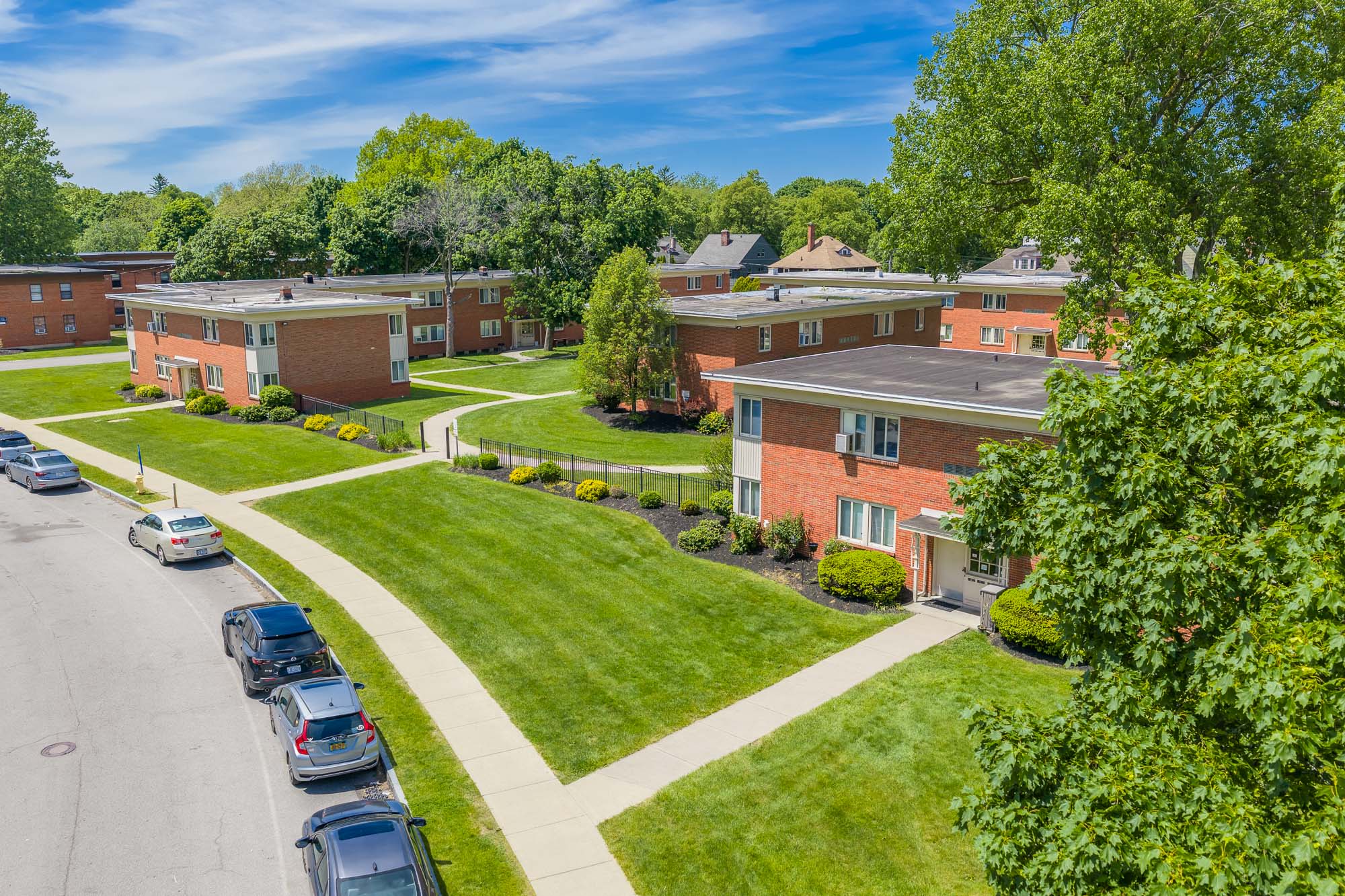 Resident courtyard with trees and green space at Highland Manor Apartments in Rochester, New York