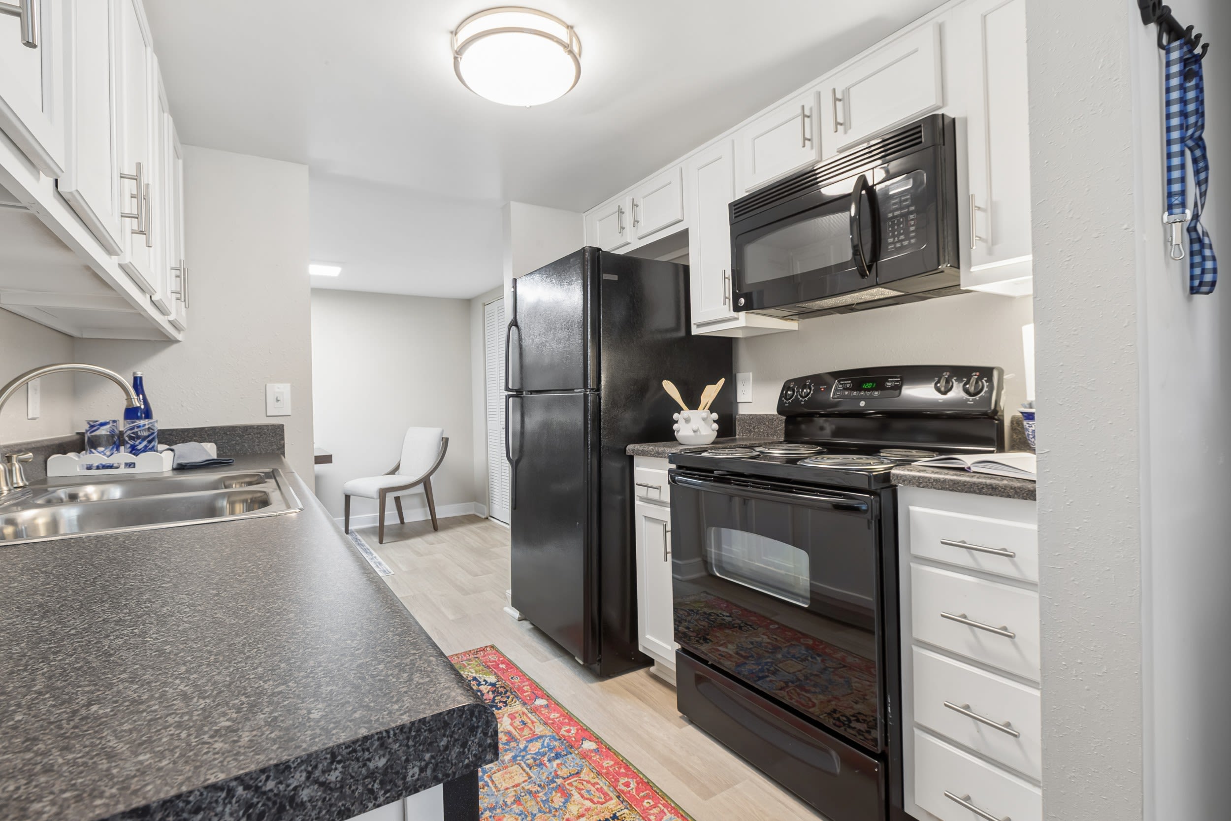 Hioaks, VA, Apartments With In-Unit Washer and Dryer - Reserve South - Galley Kitchen With White Cabinets, Energy-Efficient Appliances, and Wood-Style Flooring.