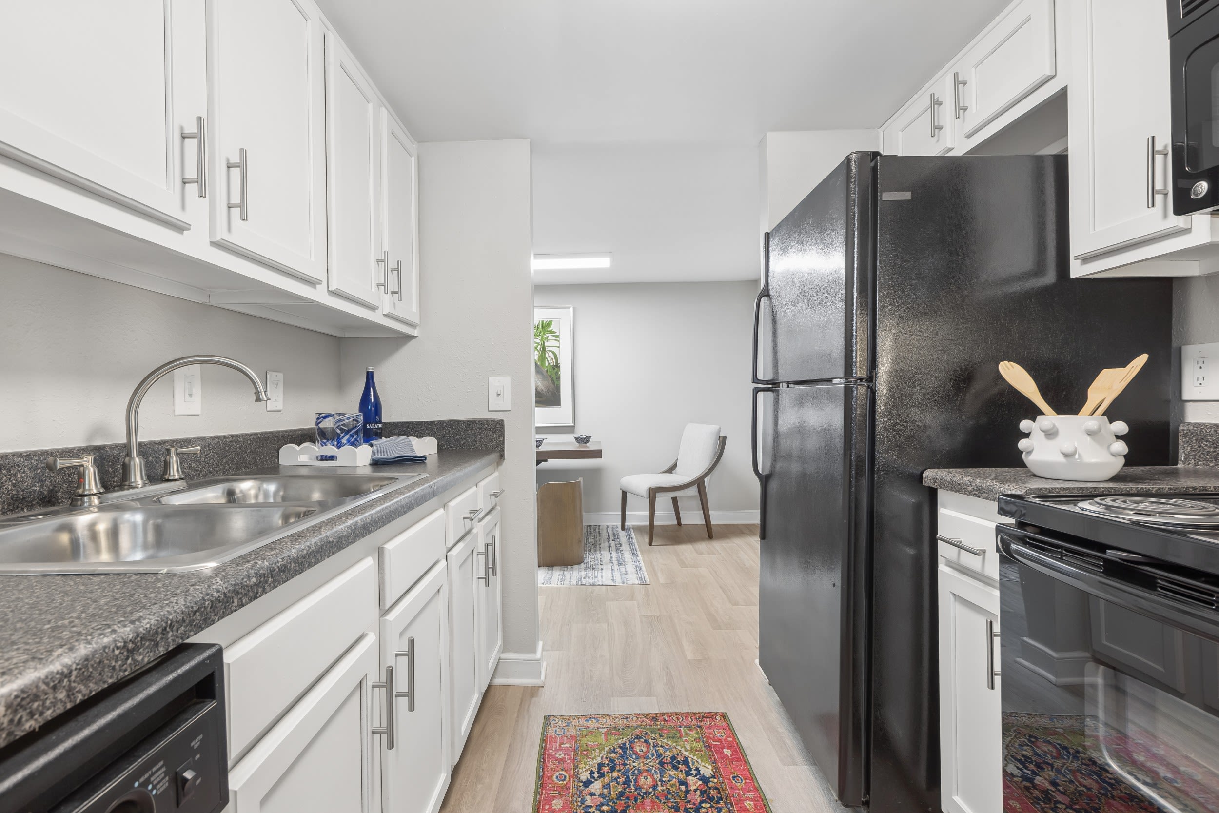 Hioaks, VA, Apartments With In-Unit Washer and Dryer - Reserve South - Galley Kitchen With White Cabinets, Energy-Efficient Appliances, and Wood-Style Flooring.
