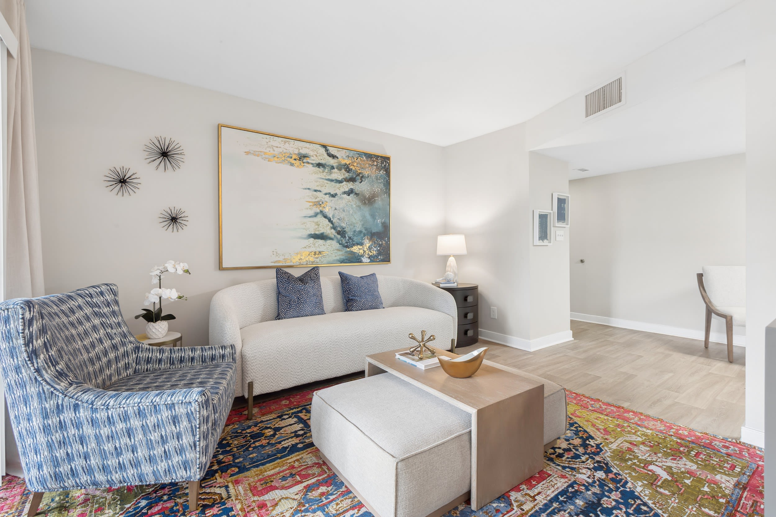 Apartments Near Richmond, VA - Reserve South - Open-Concept Living Room With Neutral Sofa, Round Coffee Table, Soft Area Rug, Wall Art, and Adjacent Dining Nook With Modern Lighting.