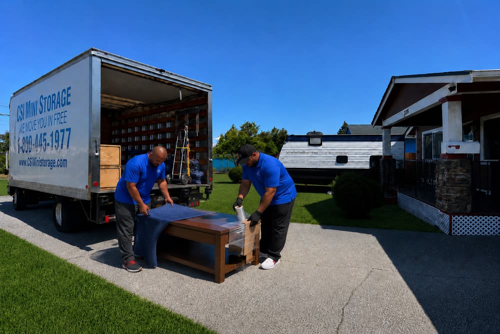 CSI Mini Storage Tacoma movers carefully wrapping a coffee table for safe transportation