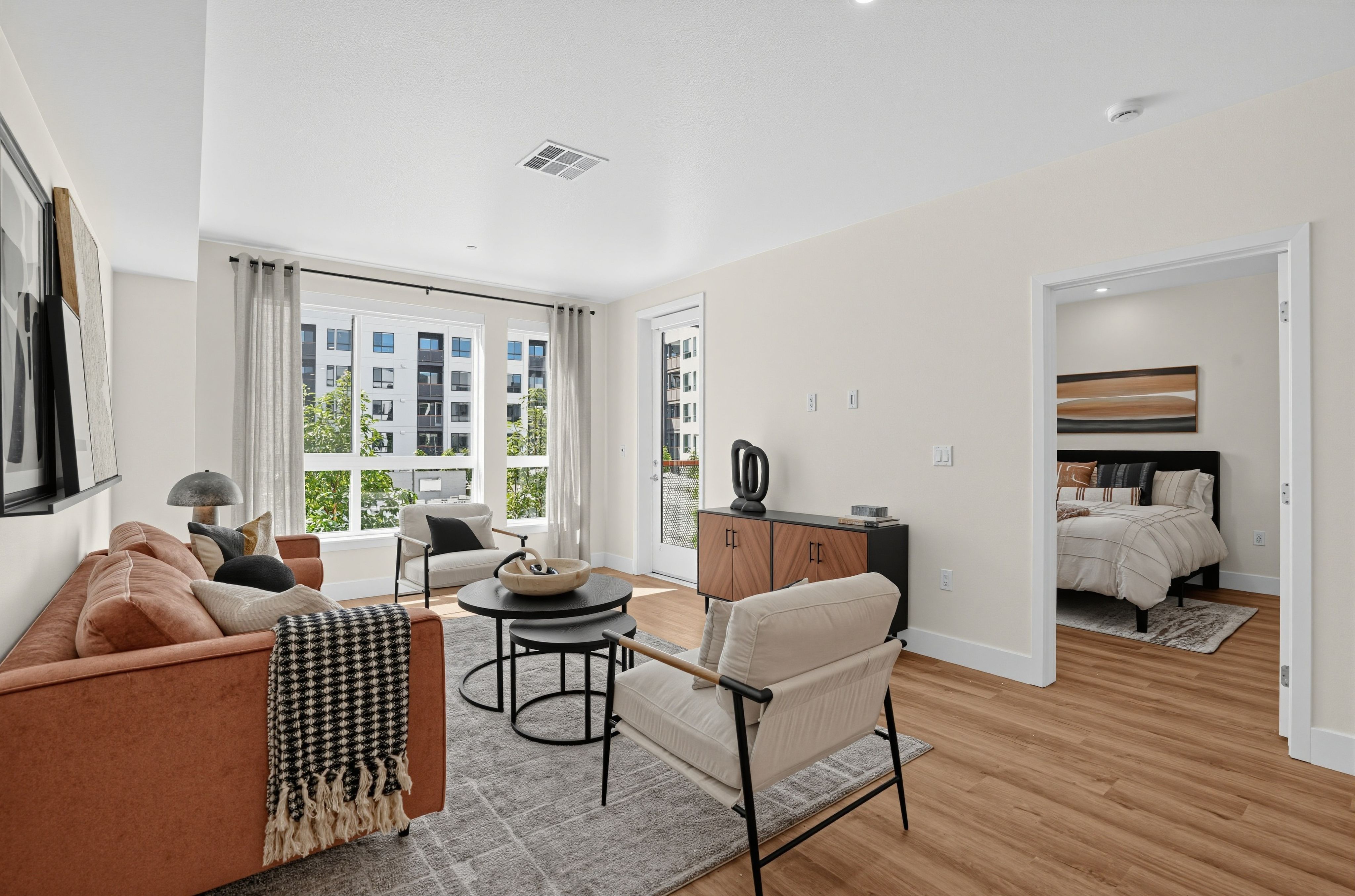 Living room with a sofa, arm chair and large windows at The Colton in Redwood City, California