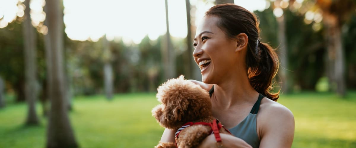 A happy resident holding her dog in dog park at The Residences at Annapolis Junction in Annapolis Junction, Maryland