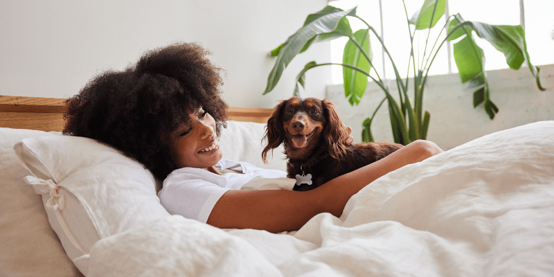 A smiling resident with her dog in bed at Constellation Park in Lemoore, California