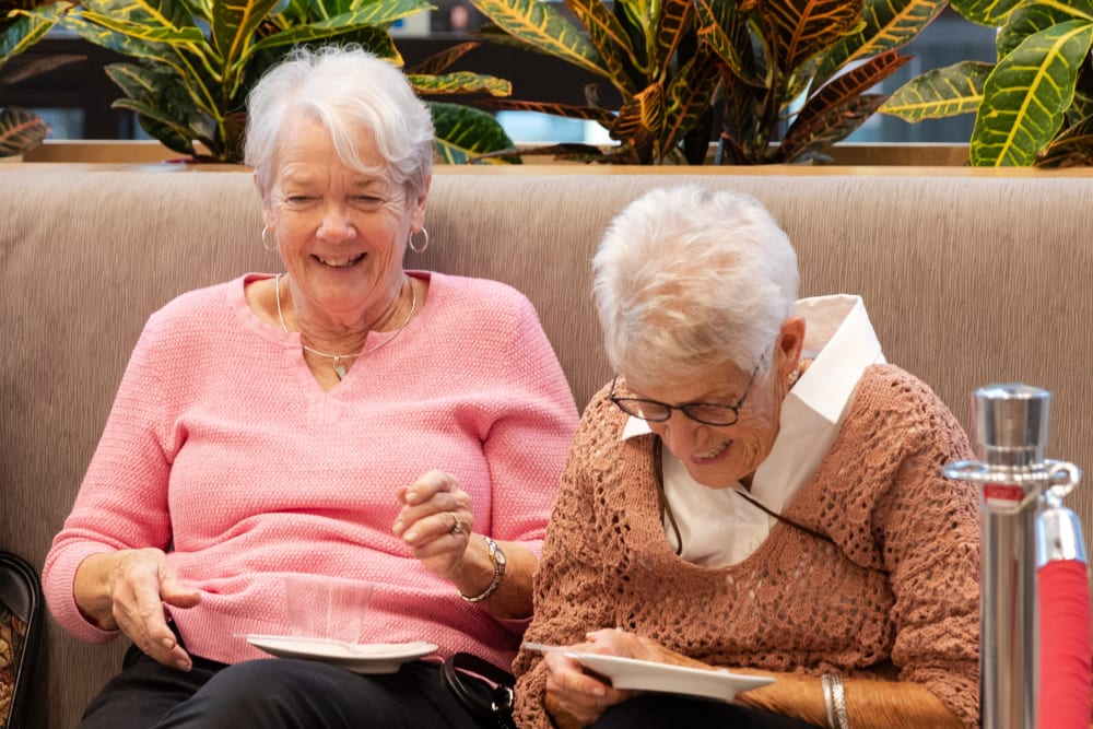 Residents laughing while having a snack and beverage together at Anthology of Millis in Millis, Massachusetts