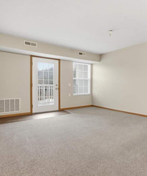 Spacious living room with carpet flooring and windows at Norwood Greene Senior Living in Marietta, Ohio