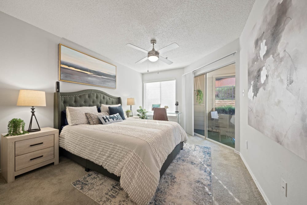 A furnished main bedroom with a door to the patio at Somerset in Lewisville, Texas