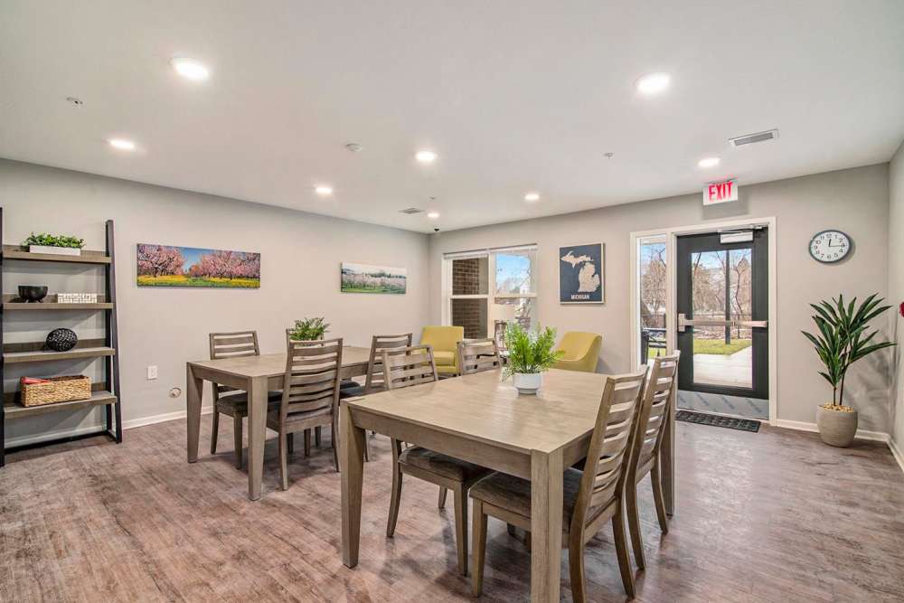 Modern community lounge with wood-style flooring, dining tables, and bright natural light from large windows at Ruth Park in Traverse City, Michigan
