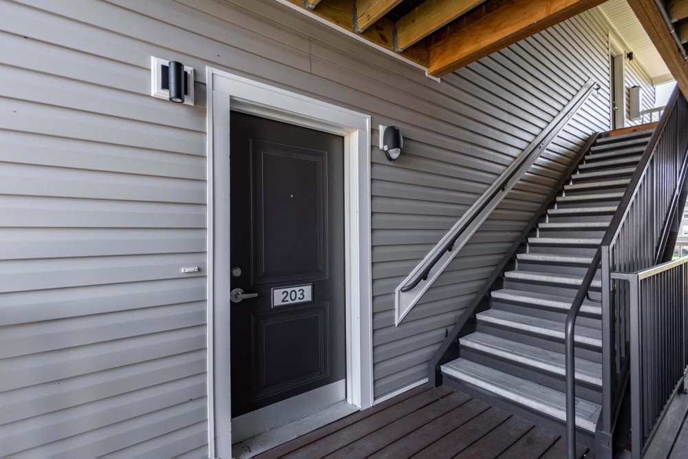 Gated entrance with a stairway leading to apartment door 203 and wooden decking at Kershaw Greene III in Athens, Ohio