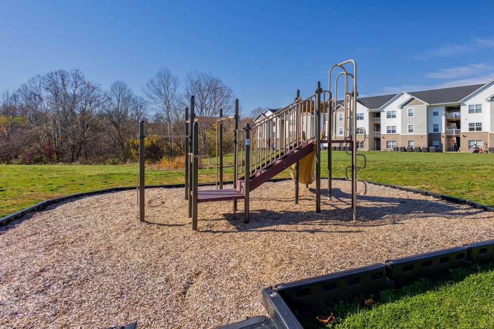 Playground with climbing structure and slide on a grassy area near apartment buildings at Kershaw Greene III in Athens, Ohio