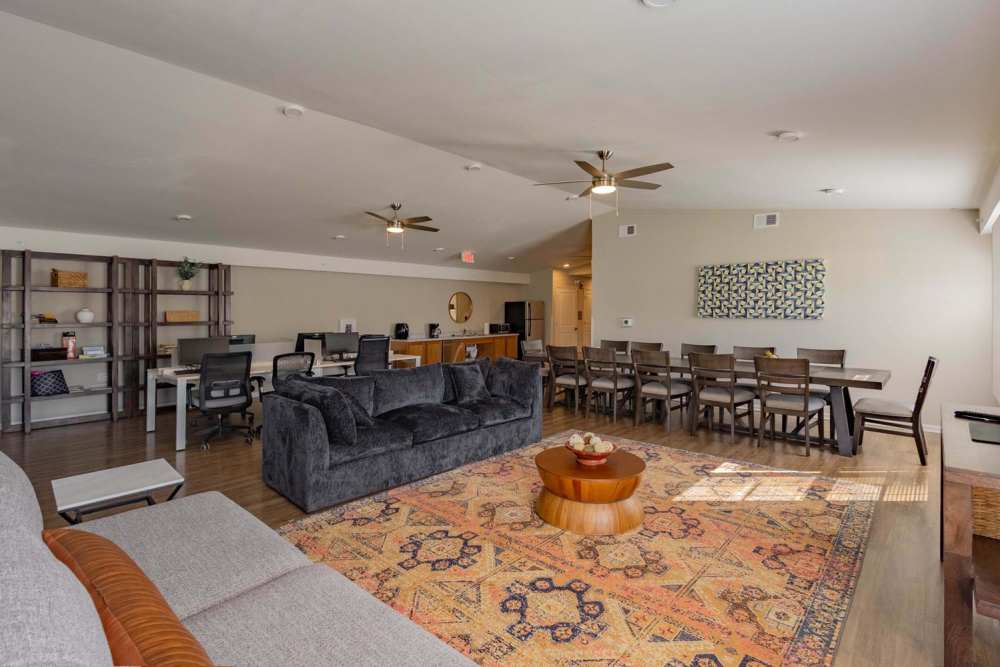 Spacious community lounge with wood-style flooring, comfortable seating, and dining area for gatherings at Kershaw Greene III in Athens, Ohio