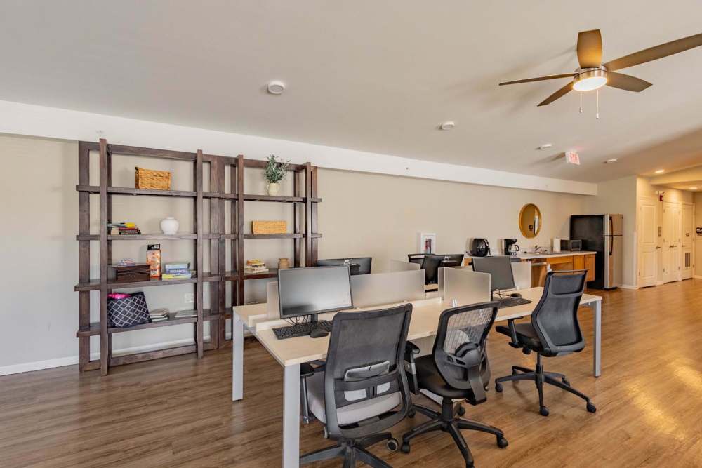 Modern coworking space with wood-style flooring, desks, and comfortable chairs, well-lit with a ceiling fan at Kershaw Greene III in Athens, Ohio
