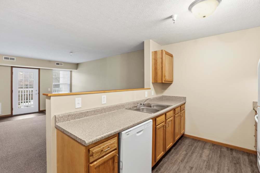 Open layout kitchen with wood-style flooring, granite countertops, and stainless steel appliances at Norwood Greene Senior Living in Marietta, Ohio