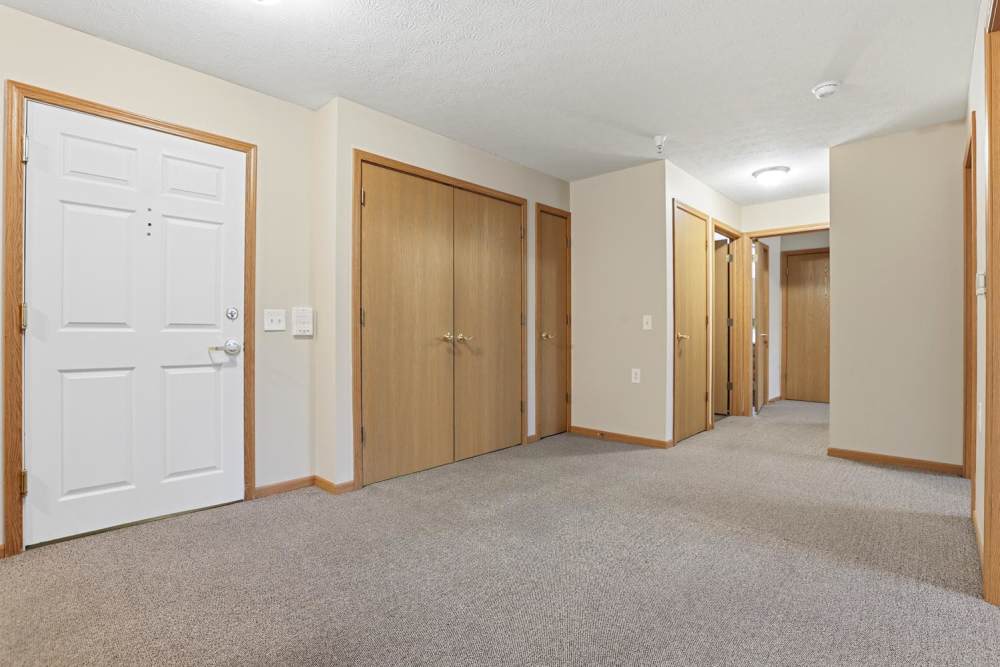 Spacious hallway with carpeted flooring and wooden doors leading to various rooms at Norwood Greene Senior Living in Marietta, Ohio