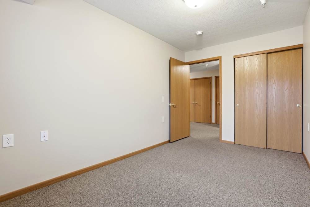 Spacious room with carpeted flooring and open doorways leading to closets at Norwood Greene Senior Living in Marietta, Ohio