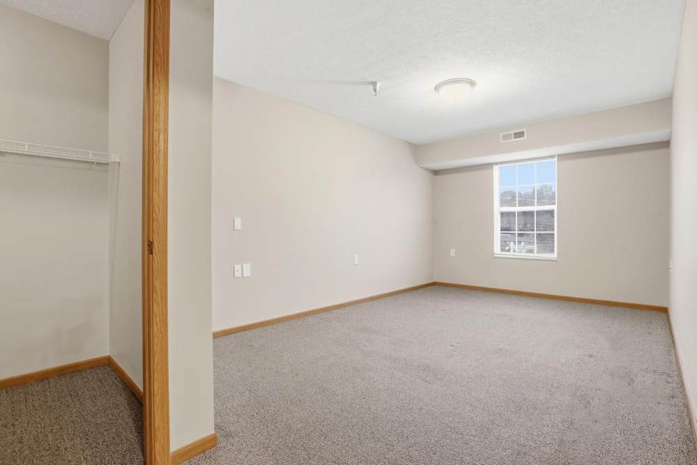 Spacious bedroom with carpet flooring and window providing natural light at Norwood Greene Senior Living in Marietta, Ohio
