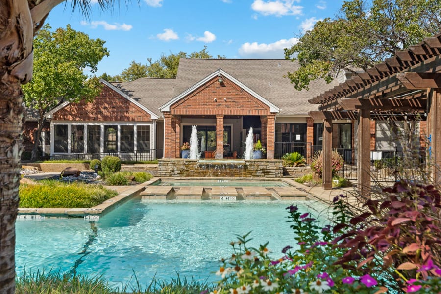 Resort-style swimming pool surrounded by meticulously landscaped grounds at The Brandt in Irving, Texas