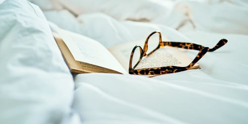 Glasses resting on a book in a bed at Laguna Senior in Los Angeles, California