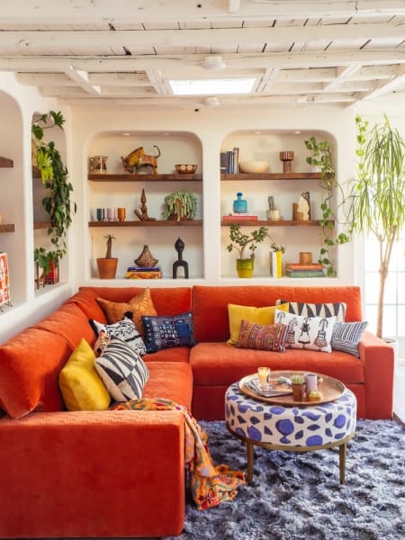 Fun orange couch featured in a living room to give energy