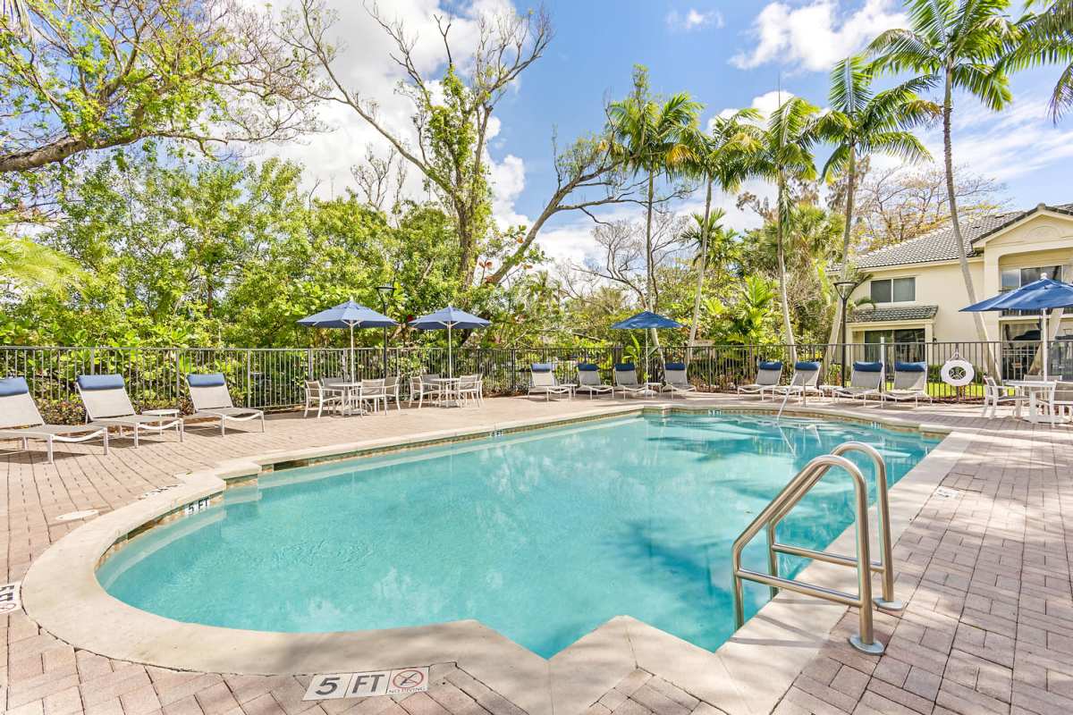 Swimming pool patio with lounge chairs and umbrella at New River Cove, Davie, Florida