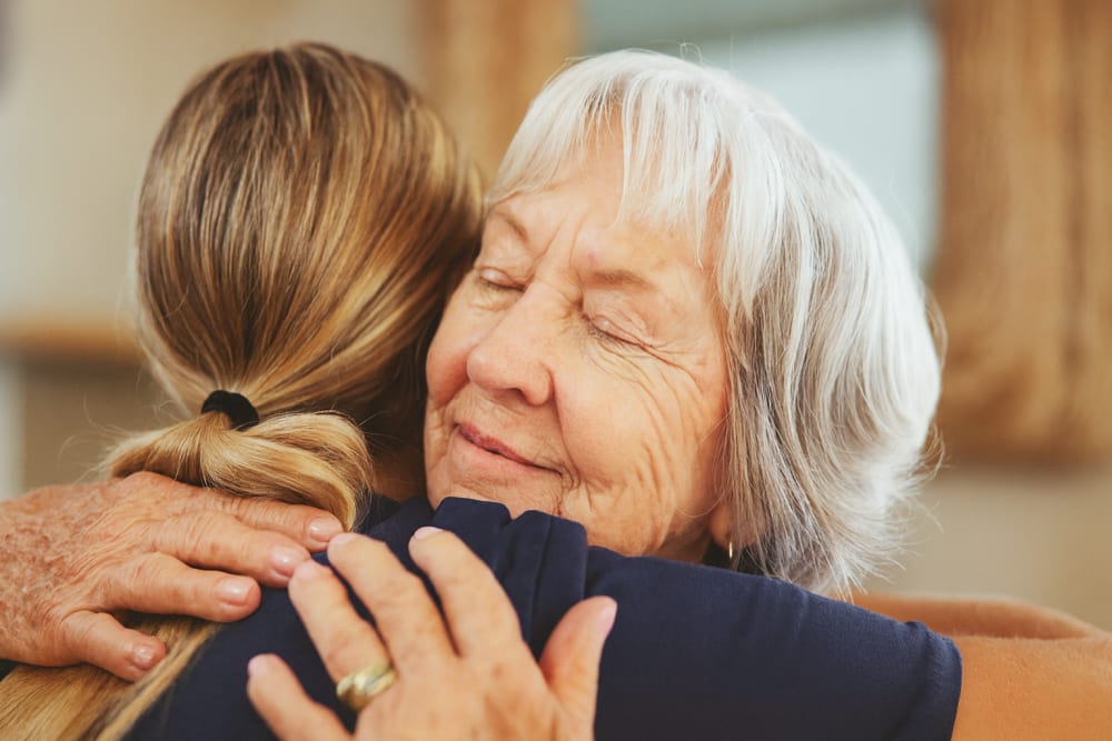 A senior citizen being comforted by a care giver