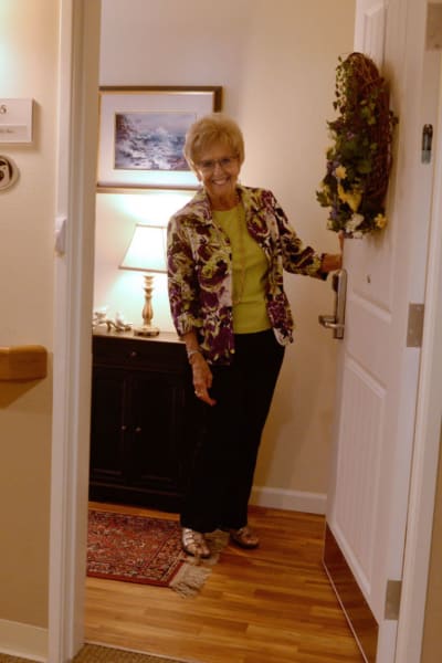 Resident holding the door to her apartment open at Quail Park at Browns Point in Tacoma, Washington
