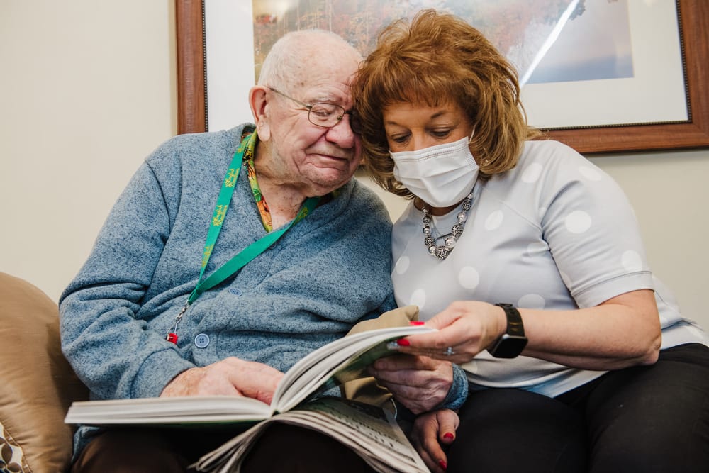 Resident looking through a photo album with a caretaker at English Meadows Crozet Campus in Crozet, Virginia