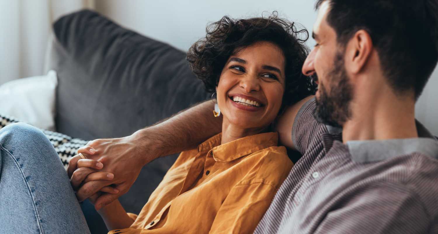 Couple sharing a laugh on the couch in their apartment at Reeds Landing Apartments in Edmond, Oklahoma 