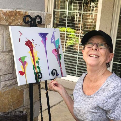 Resident showing off an abstract painting at Oxford Glen Memory Care at Sachse in Sachse, Texas